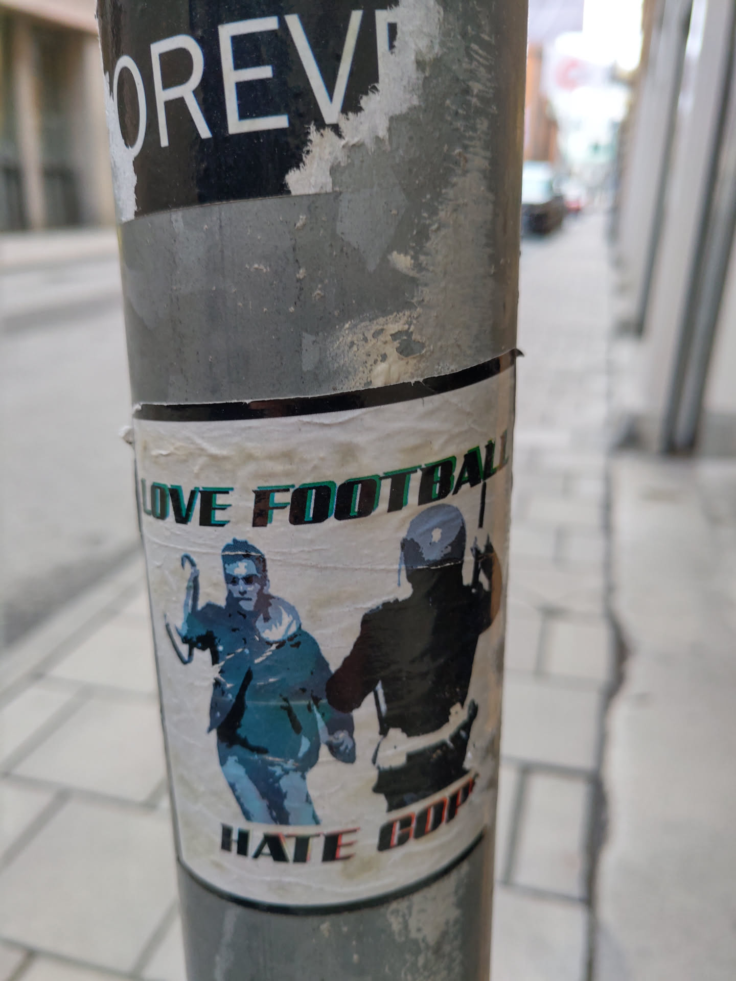 A sticker depicting a man running away from a police officer. The sticker's text is  "Love Football Hate Cops".