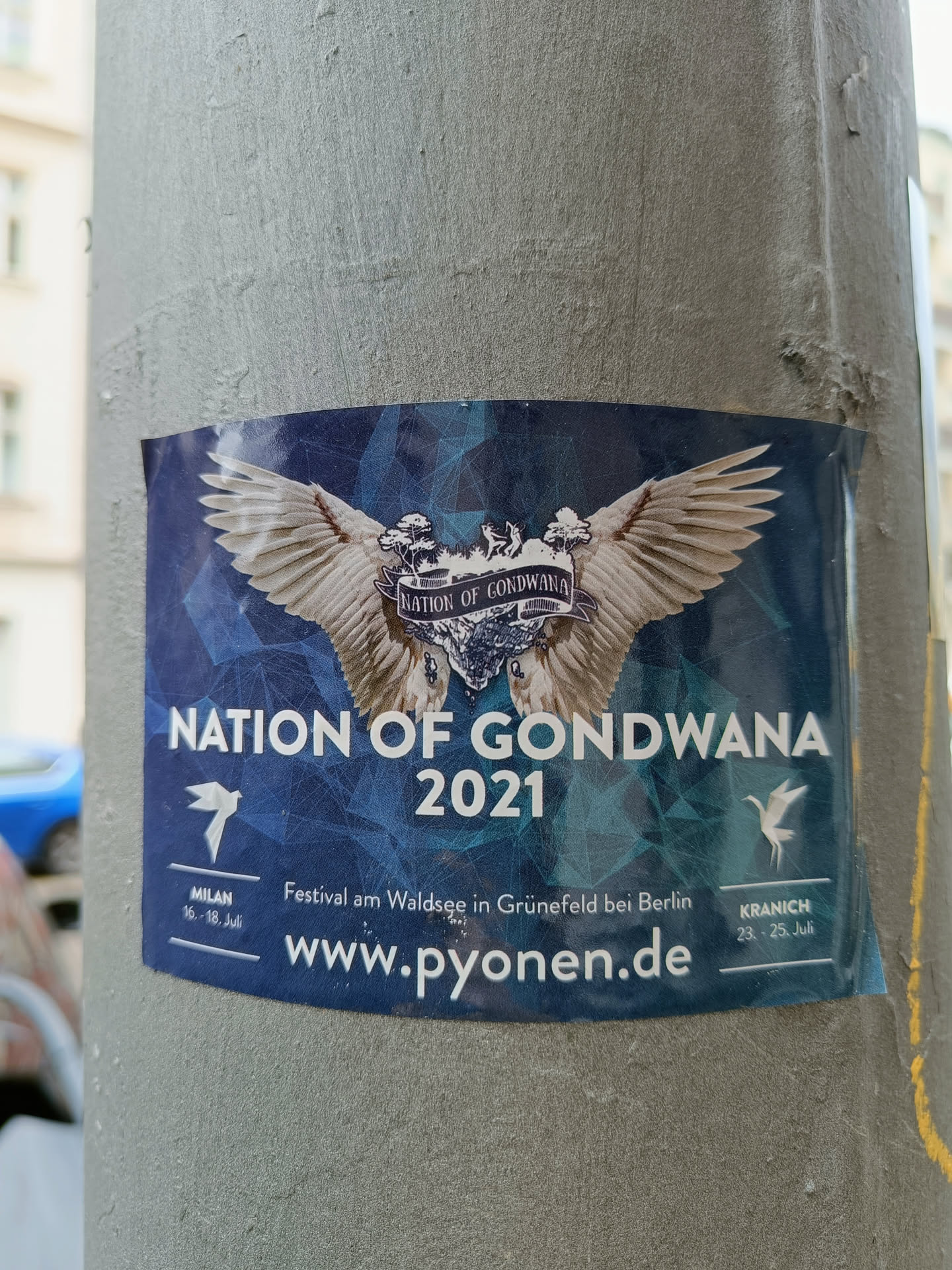A sticker advertising the Nation of Gondwana festival in 2021.  It features a pair of large wings, and the dates and locations of festivals in Milan and Berlin. The website www.pyonen.de is also included.
