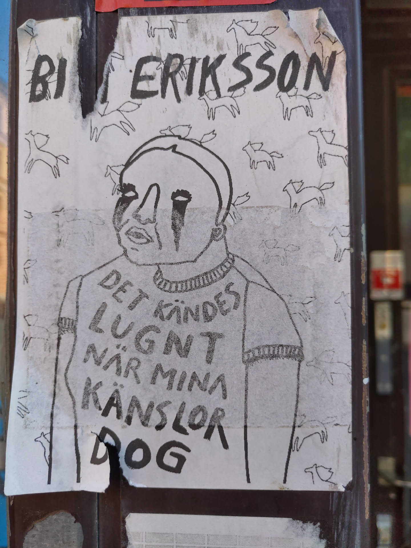 A black and white drawing of a person with tears running down their face. The person is wearing a sweater with text on it that says "Det känns lugnt när mina känslor dog" which translates to "It feels calm when my feelings die". The background is filled with small drawings of horses. The sticker is signed "BI ERIKSSON".