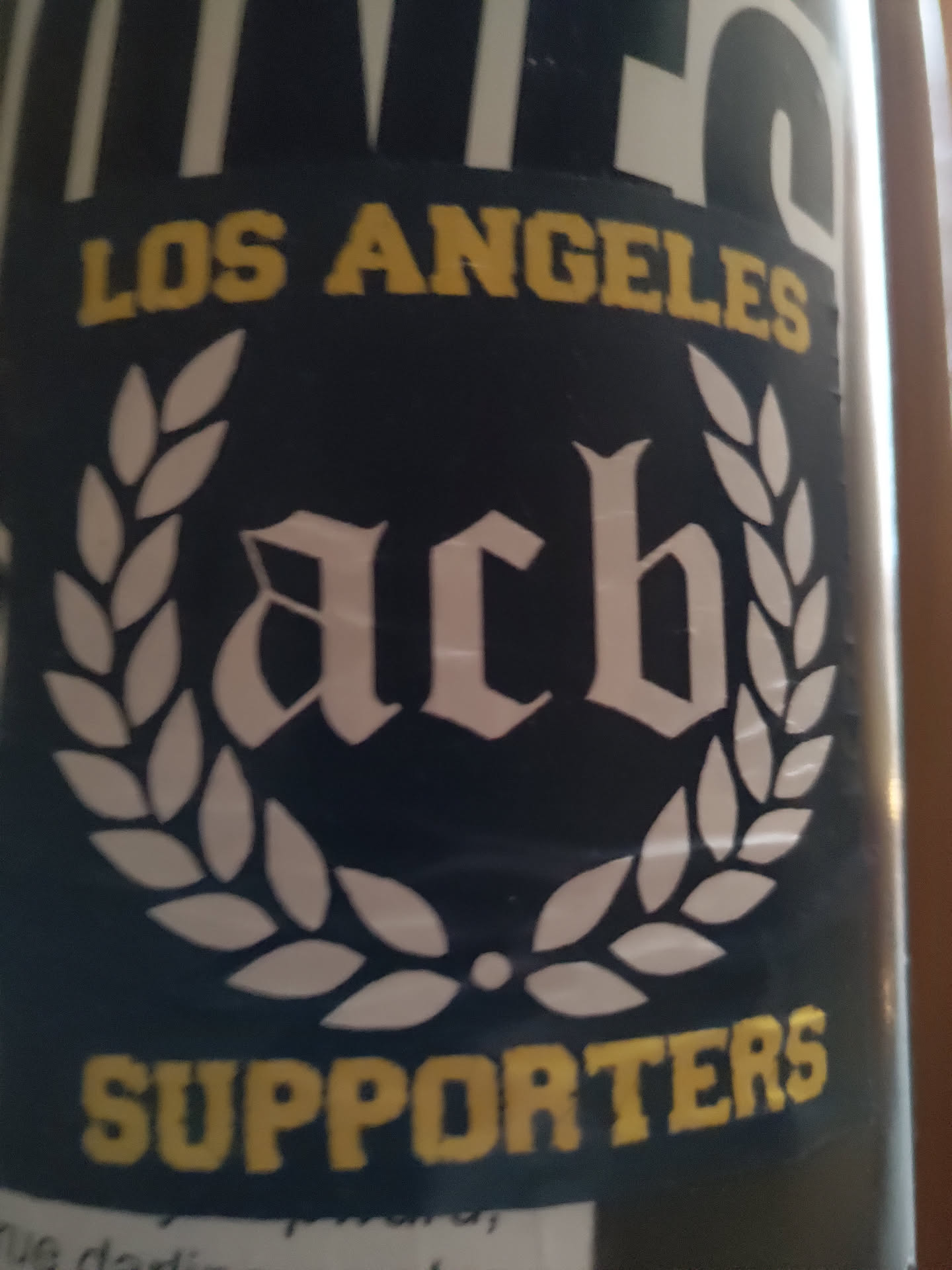A black and white sticker with a laurel wreath surrounding the letters ACB in a medieval-style font.  The words "LOS ANGELES" and "SUPPORTERS" are written in yellow above and below the emblem respectively.