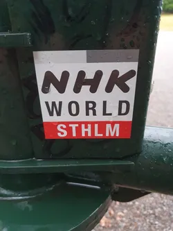 A sticker featuring the logo for NHK World, the international broadcasting service of Japan's public broadcaster, NHK.  The sticker also includes the abbreviation STHLM, which stands for Stockholm, Sweden.