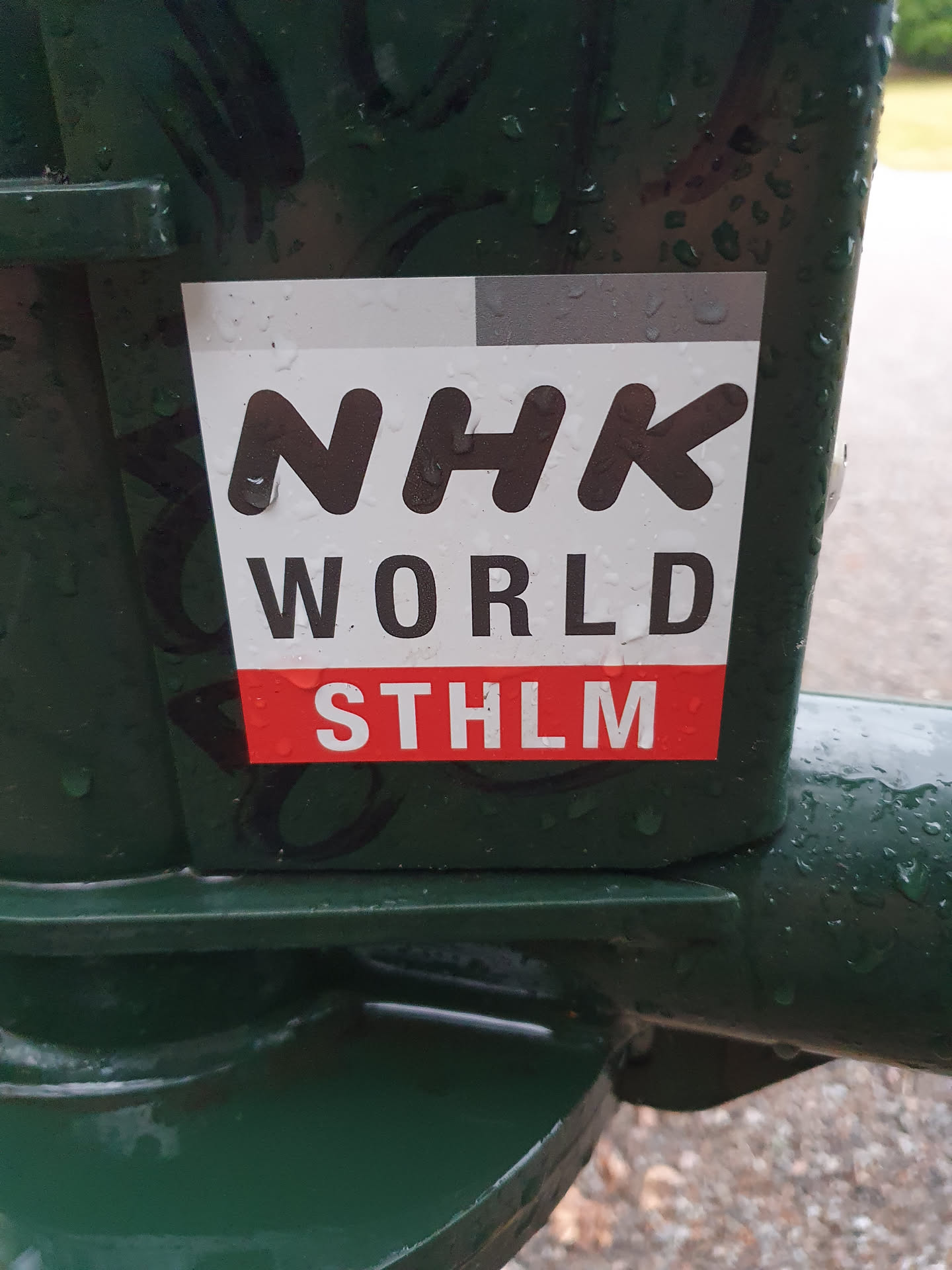 A sticker featuring the logo for NHK World, the international broadcasting service of Japan's public broadcaster, NHK.  The sticker also includes the abbreviation STHLM, which stands for Stockholm, Sweden.