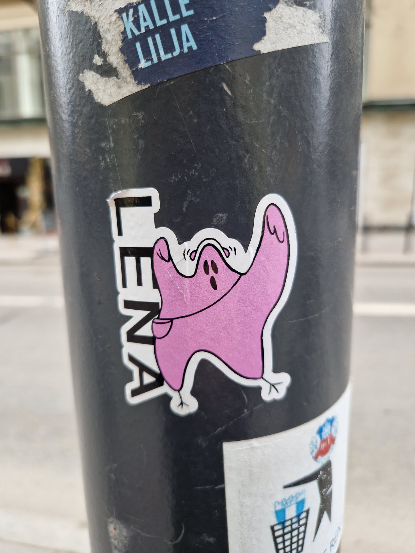A pink ghost-like creature with a small pocket is featured in this sticker. The name "Lenya" is written vertically alongside the illustration. 