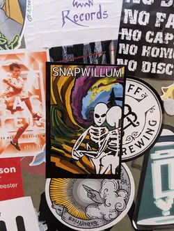 A colorful sticker showcasing artwork from Snapwillum. The design features a skeleton in a dynamic pose, set against a backdrop of swirling colors and patterns. The artist's name is clearly visible at the top.