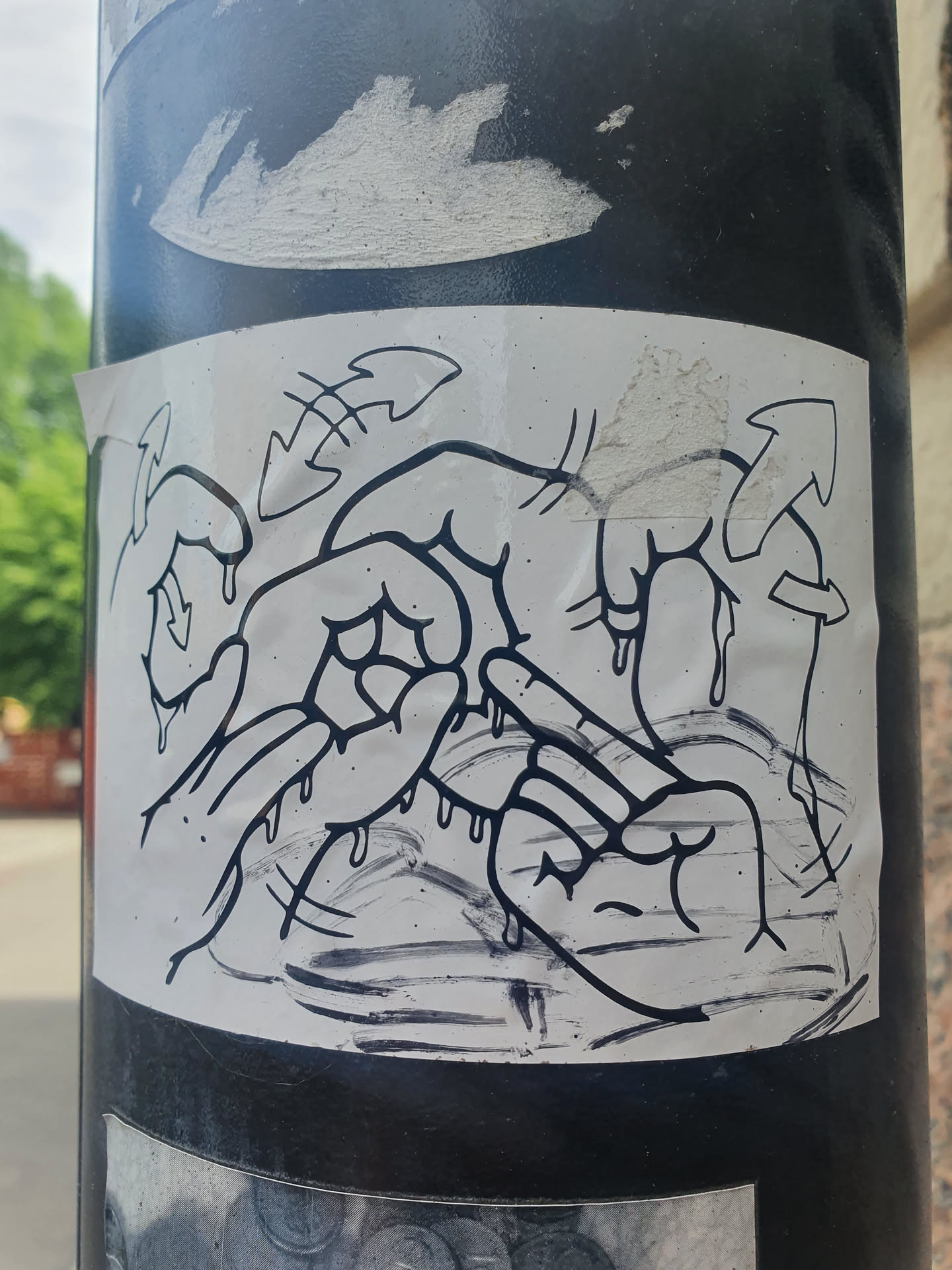 Black and white sticker with a drawing of melting hands. The style is reminiscent of graffiti art.