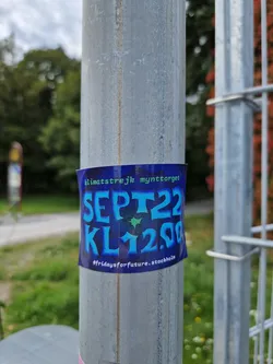 A sticker promoting a climate strike in Stockholm on September 22nd at 12:00.  The sticker is dark blue with light blue text and features a small star graphic.