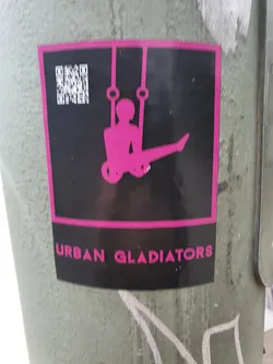 Street sticker A black and pink sticker featuring a silhouette of a person performing on rings. The text 'Urban Gladiators' is visible at the bottom. A QR code is present at the top left corner.