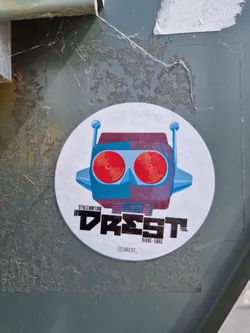Round sticker featuring a stylized robot head with red eyes. The text "DREST" is prominently displayed below the robot, along with "Style Writing" and "Since 1995". The sticker has a minimalist design with a color palette of blues, reds, and purples.