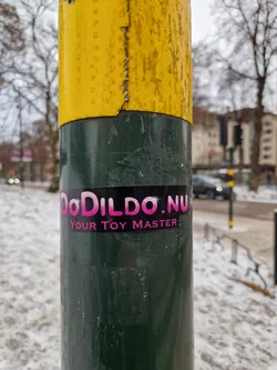 A sticker on a pole advertising DoDildo.nu, a sex toy company.