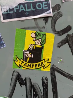 A square sticker featuring a cartoon man wearing a green plaid hat, a black jacket, and holding a to-go coffee cup. The background is green and yellow stripes, with a yellow banner at the bottom that reads "TAMPERE".