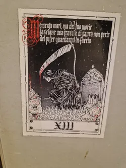 A black and white sticker depicting the Death tarot card (XIII). The grim reaper is shown with a scythe, standing over a figure in flames. Latin text surrounds the image. 