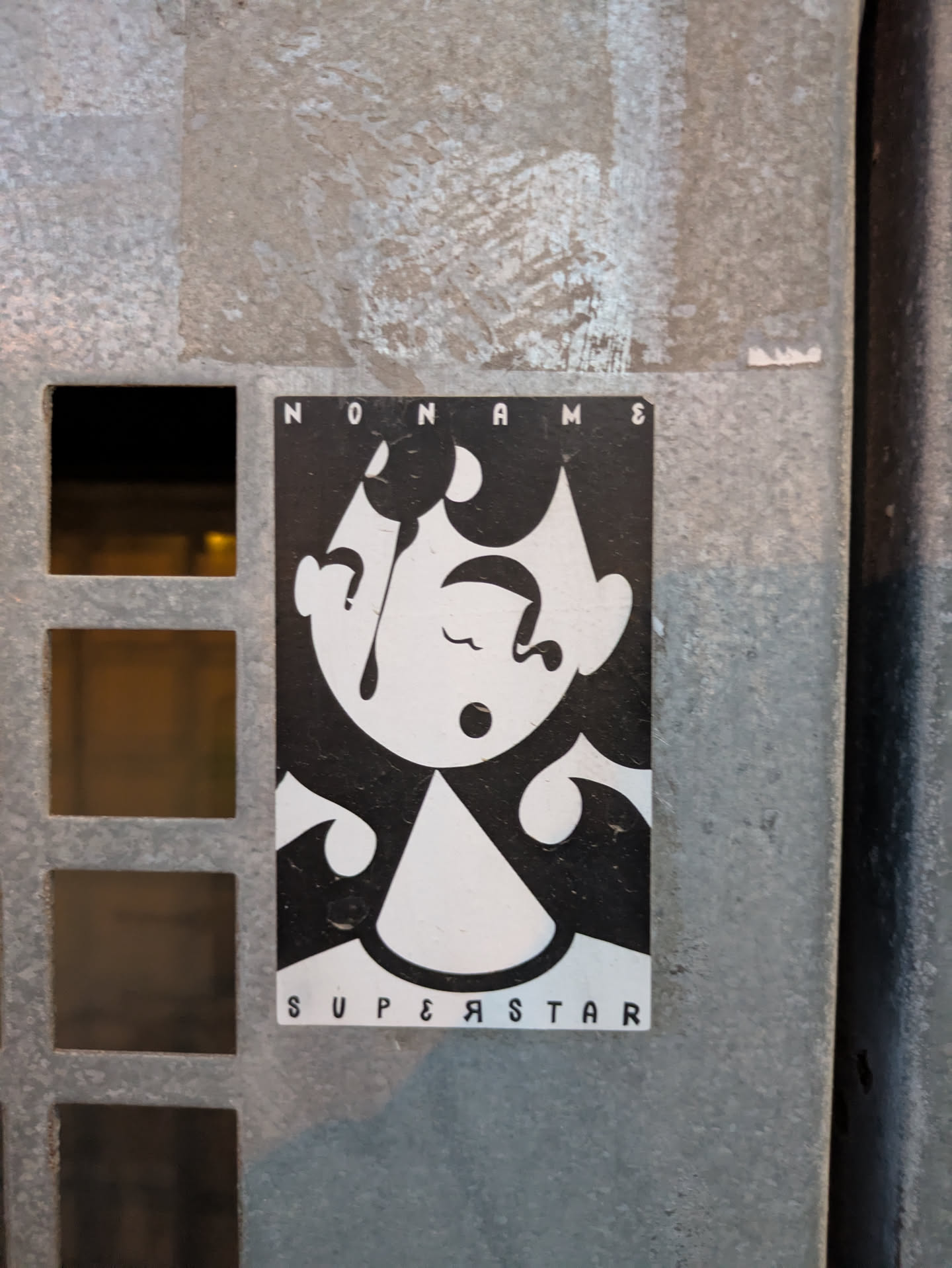 A black and white sticker depicting a cartoon-like face with its eyes closed and a teardrop, with the text 'NONAME' on top and 'SUPERSTAR' at the bottom.