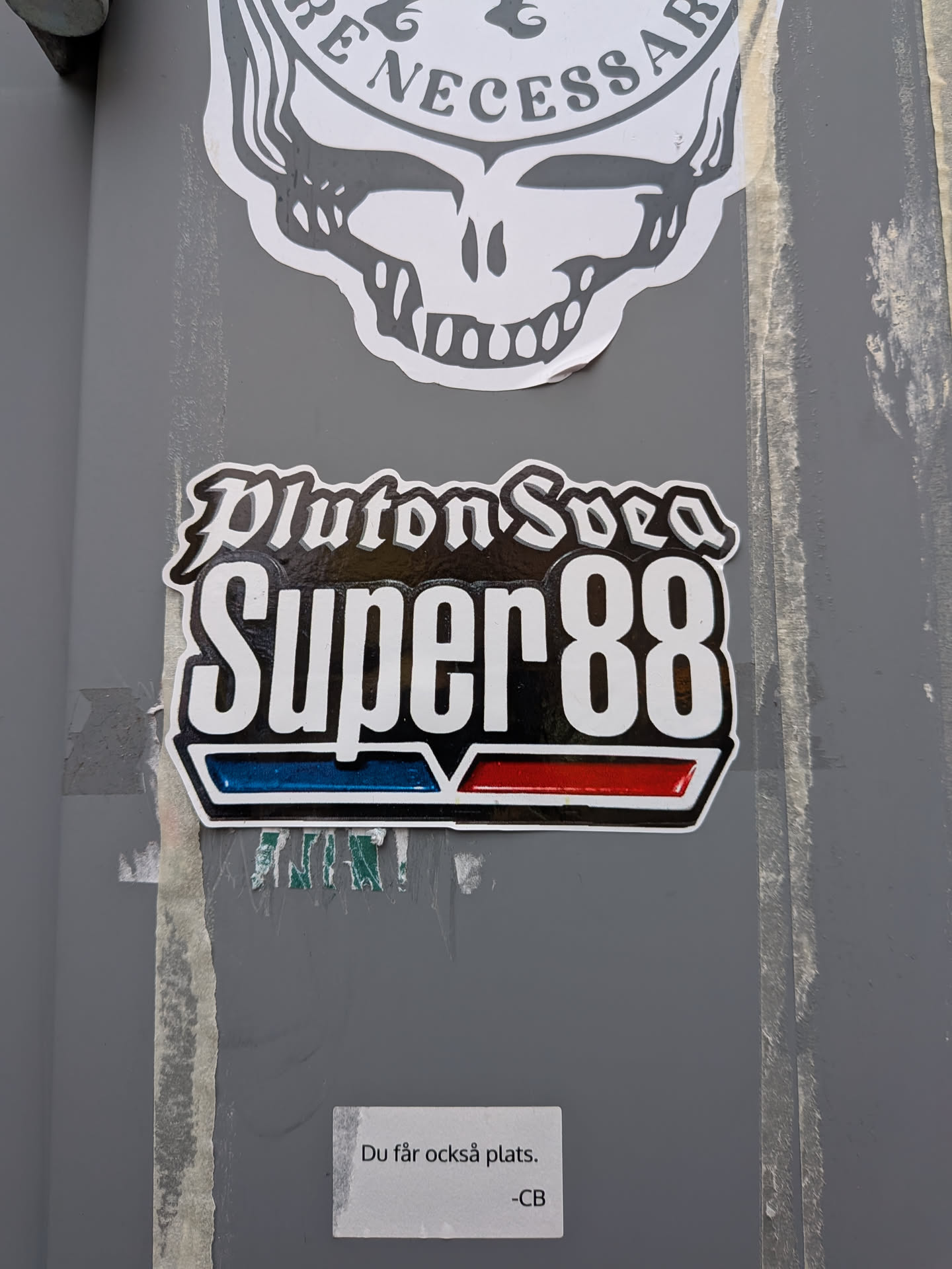 A die-cut sticker set against a grey background. At the top, the words 'Pluton Svea' are written in an ornate gothic blackletter font in white with a black fill. Below, the words 'Super 88' are displayed in prominent, tall, condensed white typography against a solid black rectangular area. Beneath the text are two slanted rectangular badge bars: a glossy blue bar on the left and a glossy red bar on the right, framed by silver-white accents, evoking vintage motor or fuel emblem branding.