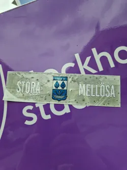 A sticker featuring the text "STORA MELLÖSA" and a small coat of arms. The sticker seems to be weathered or dirty.