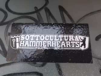 Black and white sticker with the text "SOTTOCULTURA HAMMERHEARTS" and "M'GLADBACH-BERLIN" underneath. It features a logo with a shield-like design and a bear figure.