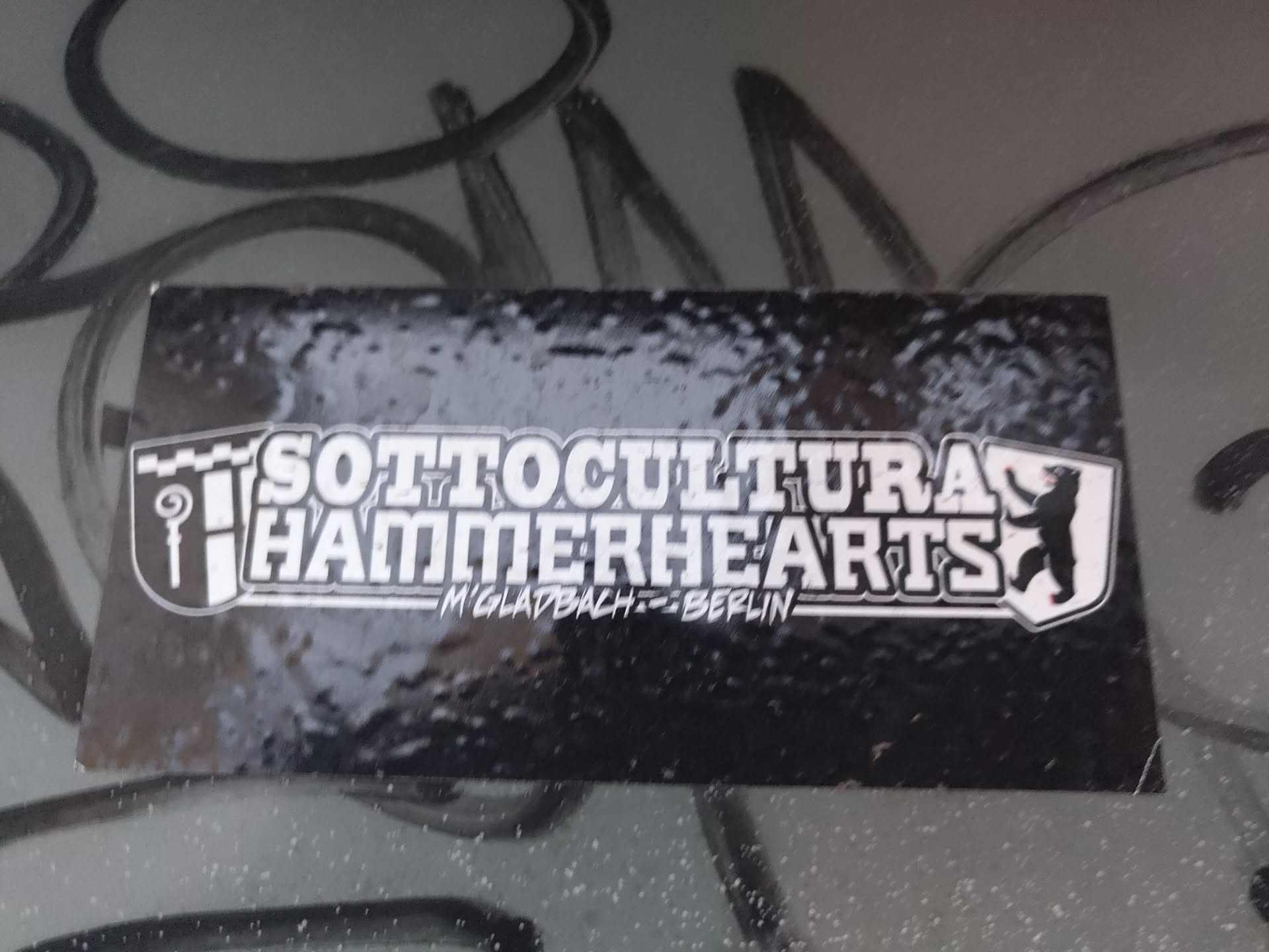 Black and white sticker with the text "SOTTOCULTURA HAMMERHEARTS" and "M'GLADBACH-BERLIN" underneath. It features a logo with a shield-like design and a bear figure.