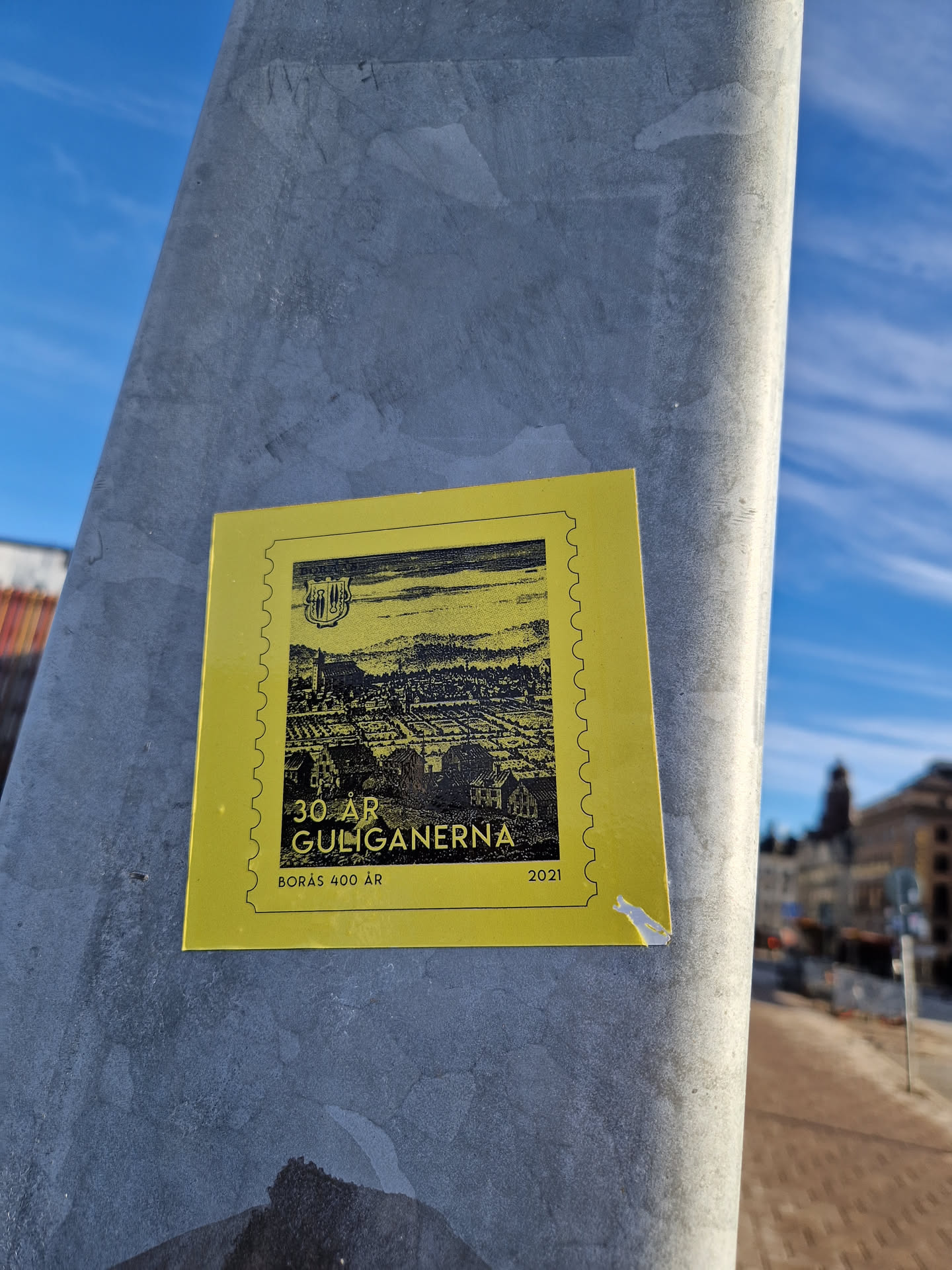 A yellow sticker commemorating 30 years of Guliganerna and 400 years of Borås. The sticker features a black and white illustration of a cityscape.