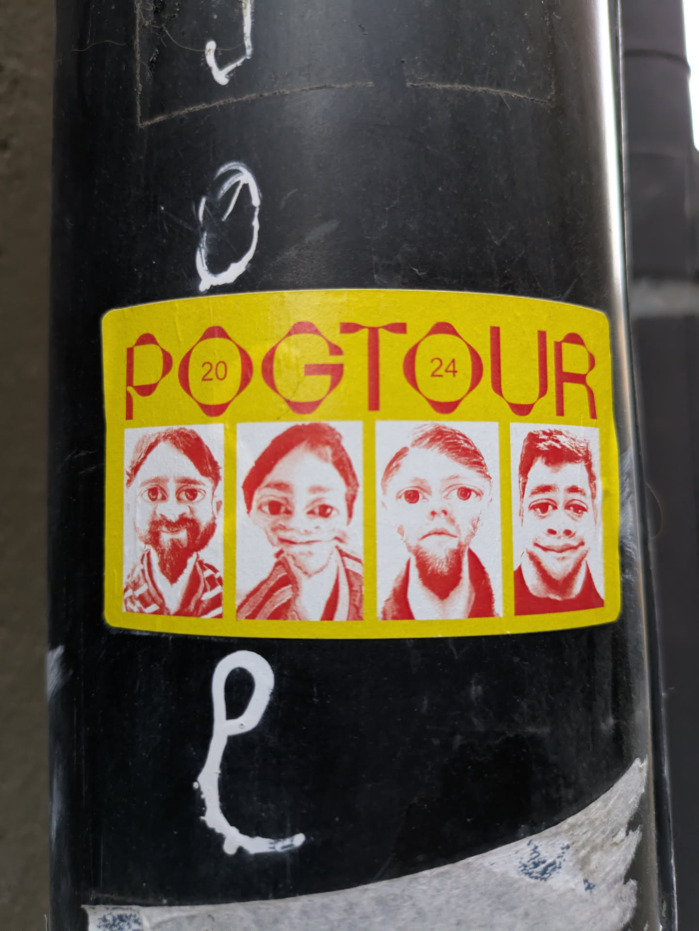 Yellow sticker with red text and four portraits. The text says POGTOUR with the numbers 20 and 24 on each side. The portraits appear to be stylized or caricatured faces.