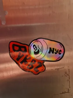 Holographic sticker with an illustration of a can of soda and the text BKBTZ. The can has the text 'Nyc' on it. The sticker has a red drip effect at the bottom.