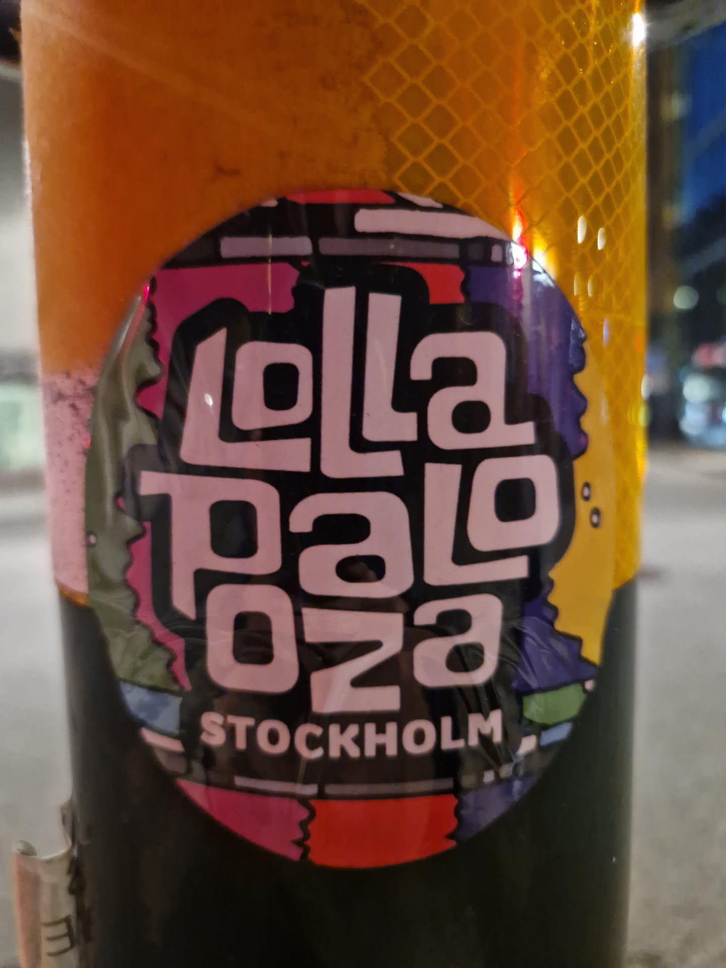 Round sticker with the text "Lollapalooza 023" in a stylized font and the word "Stockholm" below it. The background is colorful and abstract.