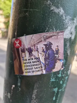 A sticker depicting a scene from the 2019 Hong Kong protests, featuring MTR (Mass Transit Railway) staff and protestors.  Text on the sticker reads: "The MTR has never been concerned about safety and security."  The numbers #721 and #831 are also present, likely referencing specific dates or events related to the protests.