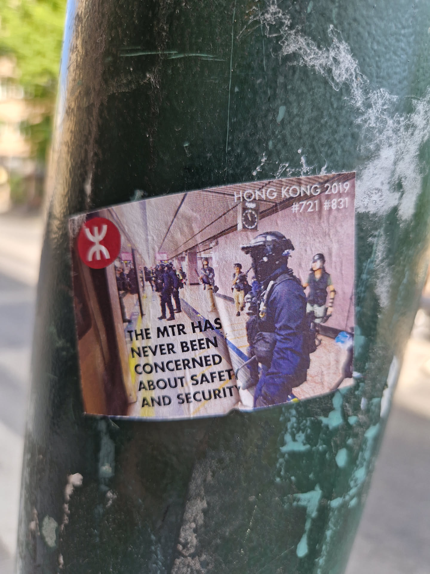 A sticker depicting a scene from the 2019 Hong Kong protests, featuring MTR (Mass Transit Railway) staff and protestors.  Text on the sticker reads: "The MTR has never been concerned about safety and security."  The numbers #721 and #831 are also present, likely referencing specific dates or events related to the protests.