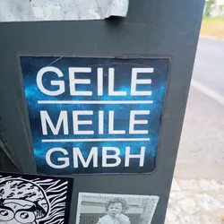 A sticker with the text "GEILE MEILE GMBH" on a blue nebula background.  The text is in white, with each word on a separate line. GMBH is a common abbreviation for a limited liability company in German.