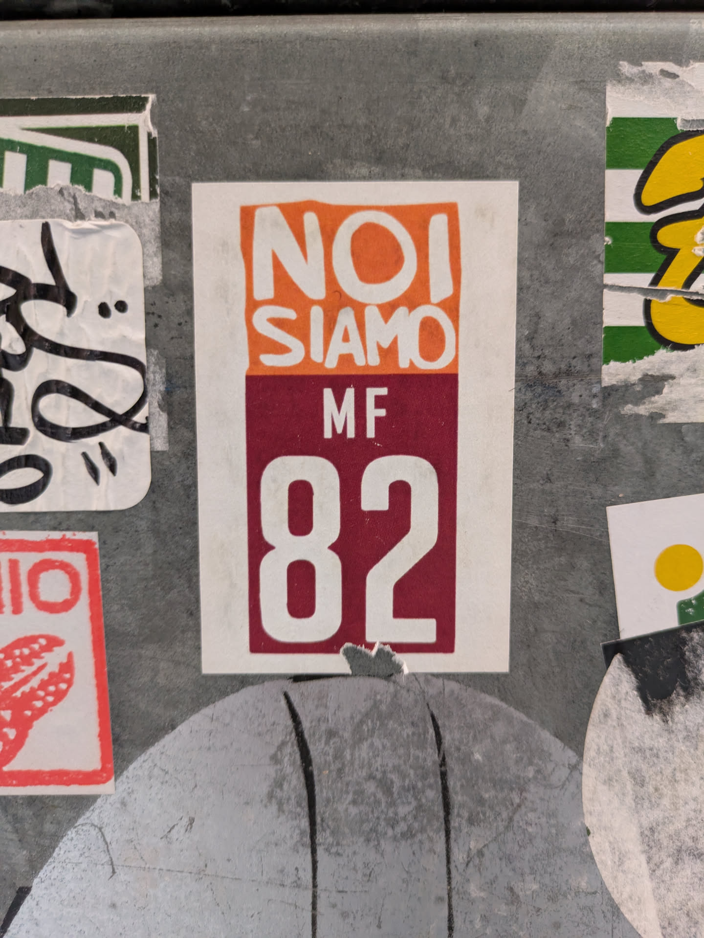 A sticker with the text "NOI SIAMO" over "MF 82". The sticker has an orange and burgundy color scheme.