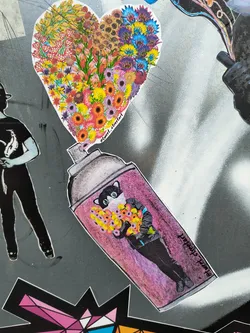Street sticker A sticker featuring a spray can with a heart-shaped bouquet of flowers pouring out of it. A cat-like figure is inside the spray can, holding the flowers. The style is colorful and whimsical.