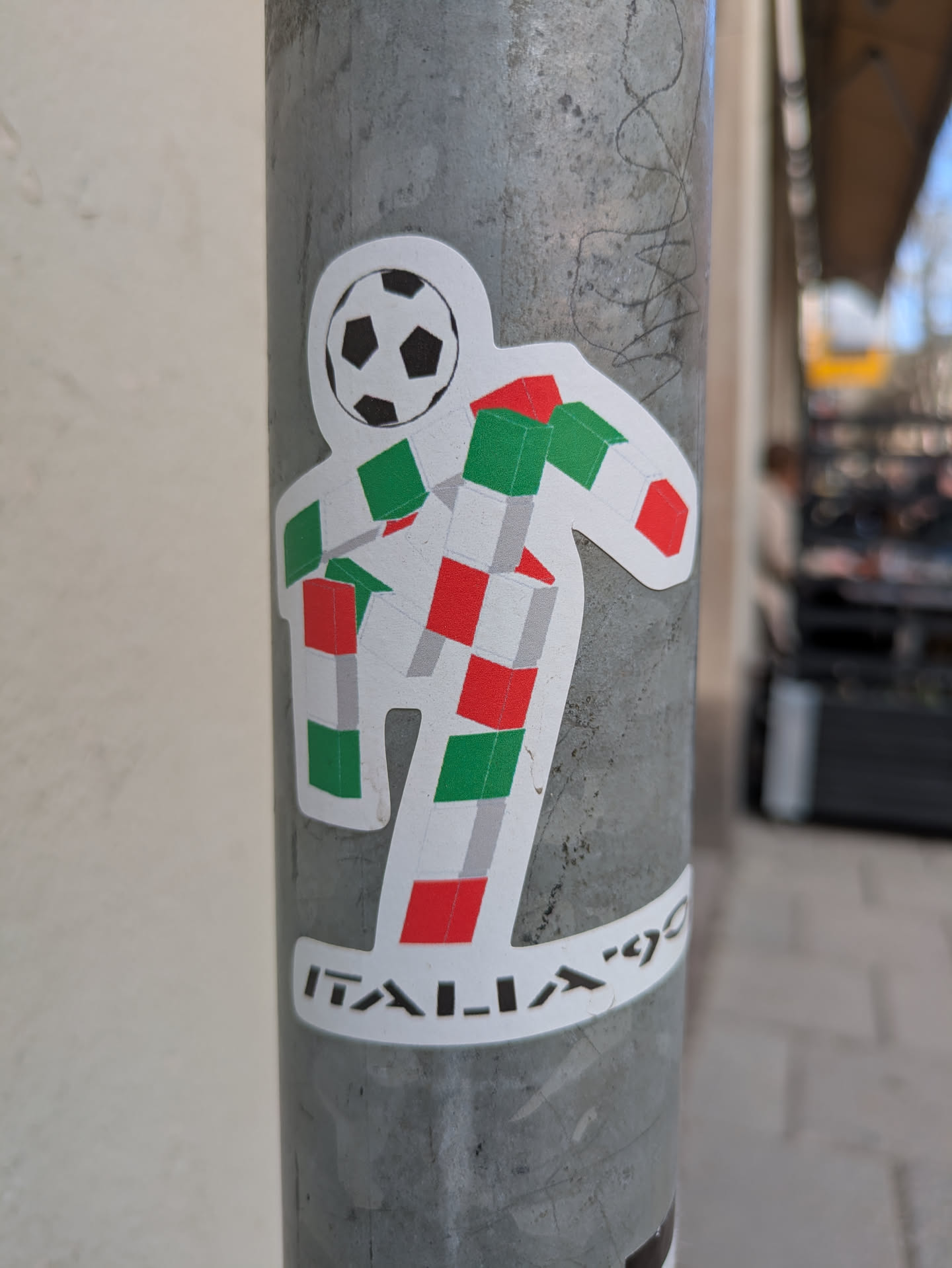 The sticker shows the Italia '90 World Cup mascot, a white figure with a soccer ball for a head and a body constructed of red, white, and green cubes, resembling the Italian flag.  The words 'ITALIA '90' are printed below the figure.