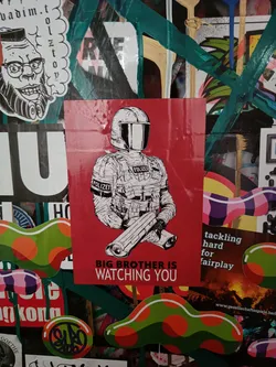 A red sticker with a black and white illustration of a riot police officer holding a weapon. The text "Big Brother Is Watching You" is written below the illustration.