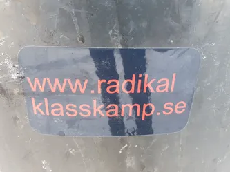 A black sticker with the text "www.radikal klasskamp.se" written in orange.  The website appears to be related to radical class struggle.