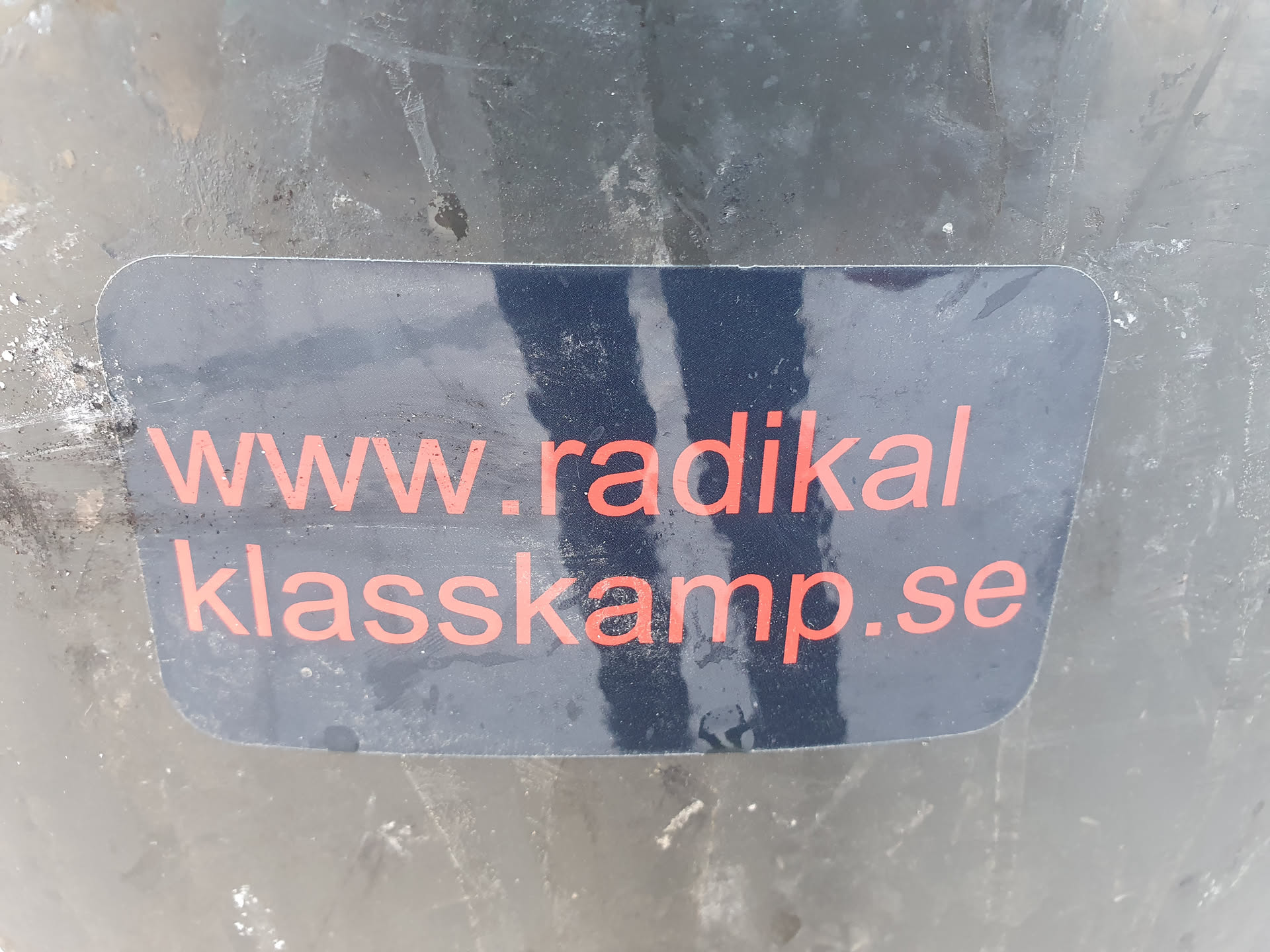A black sticker with the text "www.radikal klasskamp.se" written in orange.  The website appears to be related to radical class struggle.
