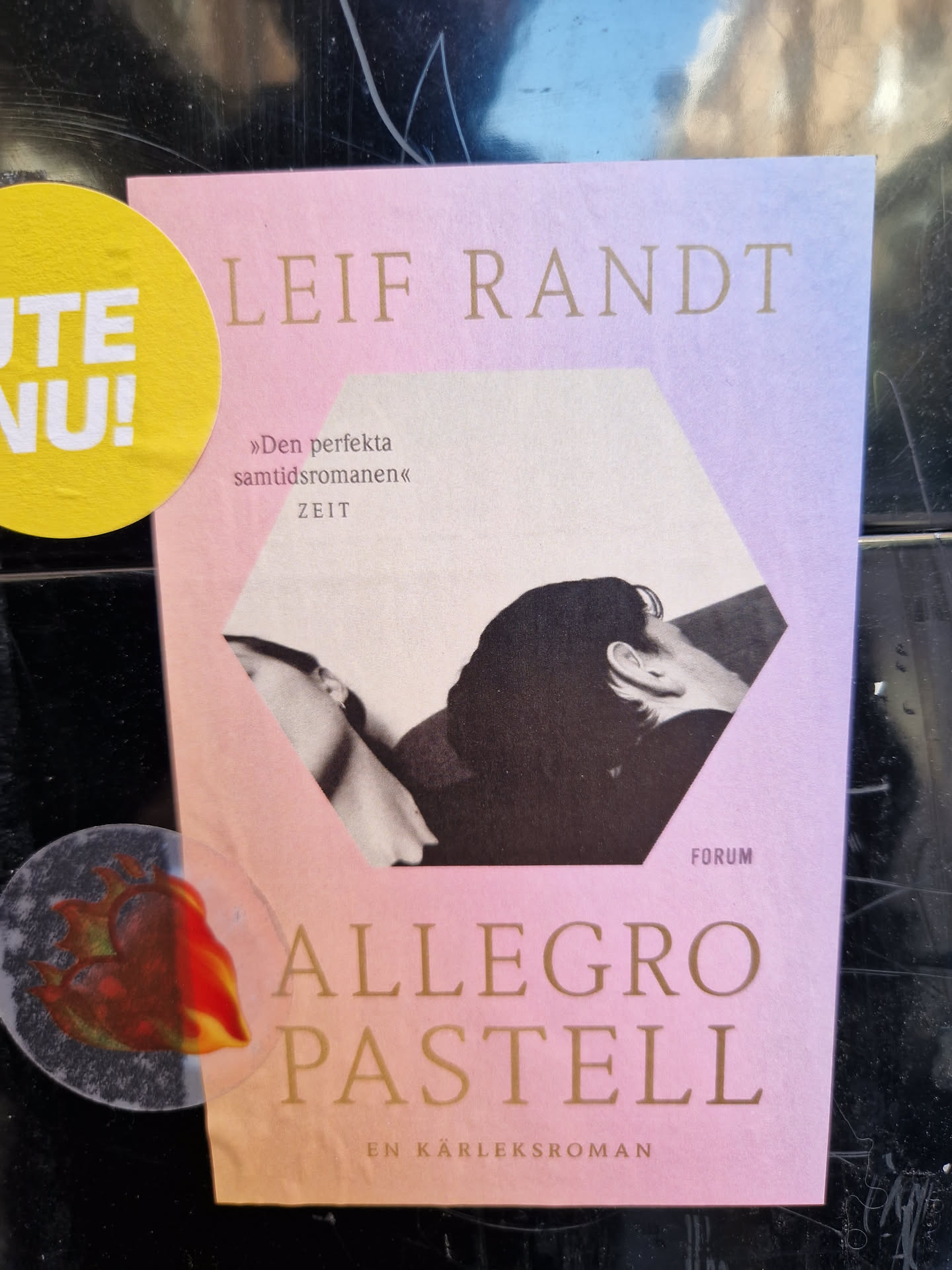 Book cover sticker for the novel "Allegro Pastell" by Leif Randt. The sticker features a pastel pink and purple color scheme with a black and white photo of two people.  The text on the sticker includes the author's name, the title, and a description of the book as "a perfect contemporary novel".