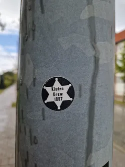 A black and white circular sticker with a sheriff's badge design.  It features a five-pointed star with the text 'Kluden Krewe 1887' inside.