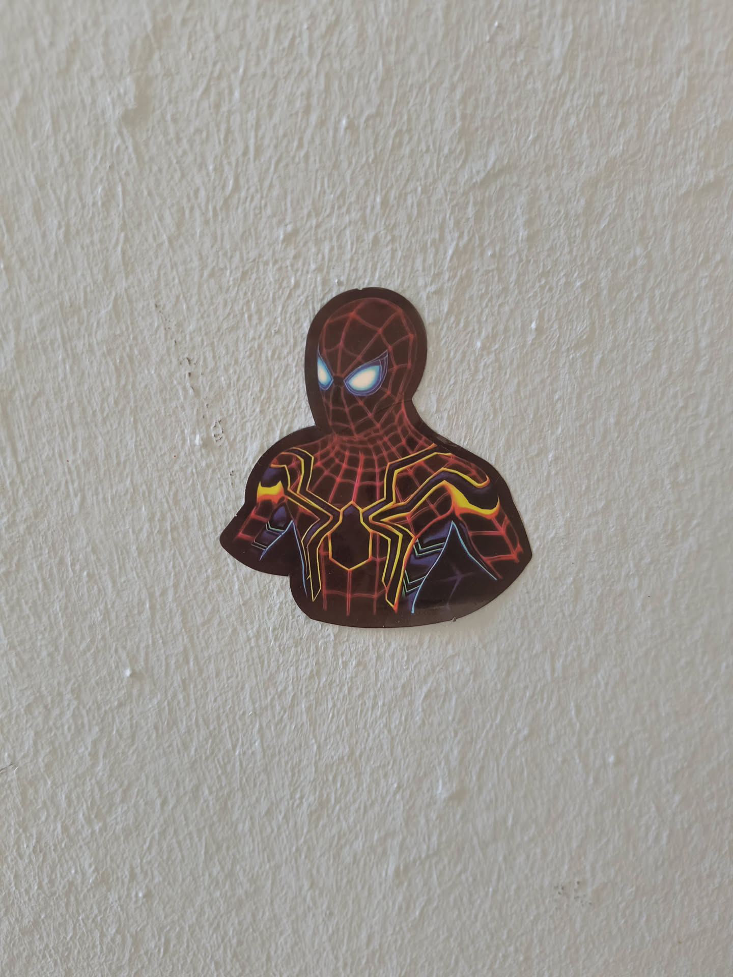 A vinyl sticker featuring the Iron Spider-Man suit from Marvel Comics and the Marvel Cinematic Universe. The sticker is predominantly red and gold with black accents, and depicts Spider-Man's face and upper body.