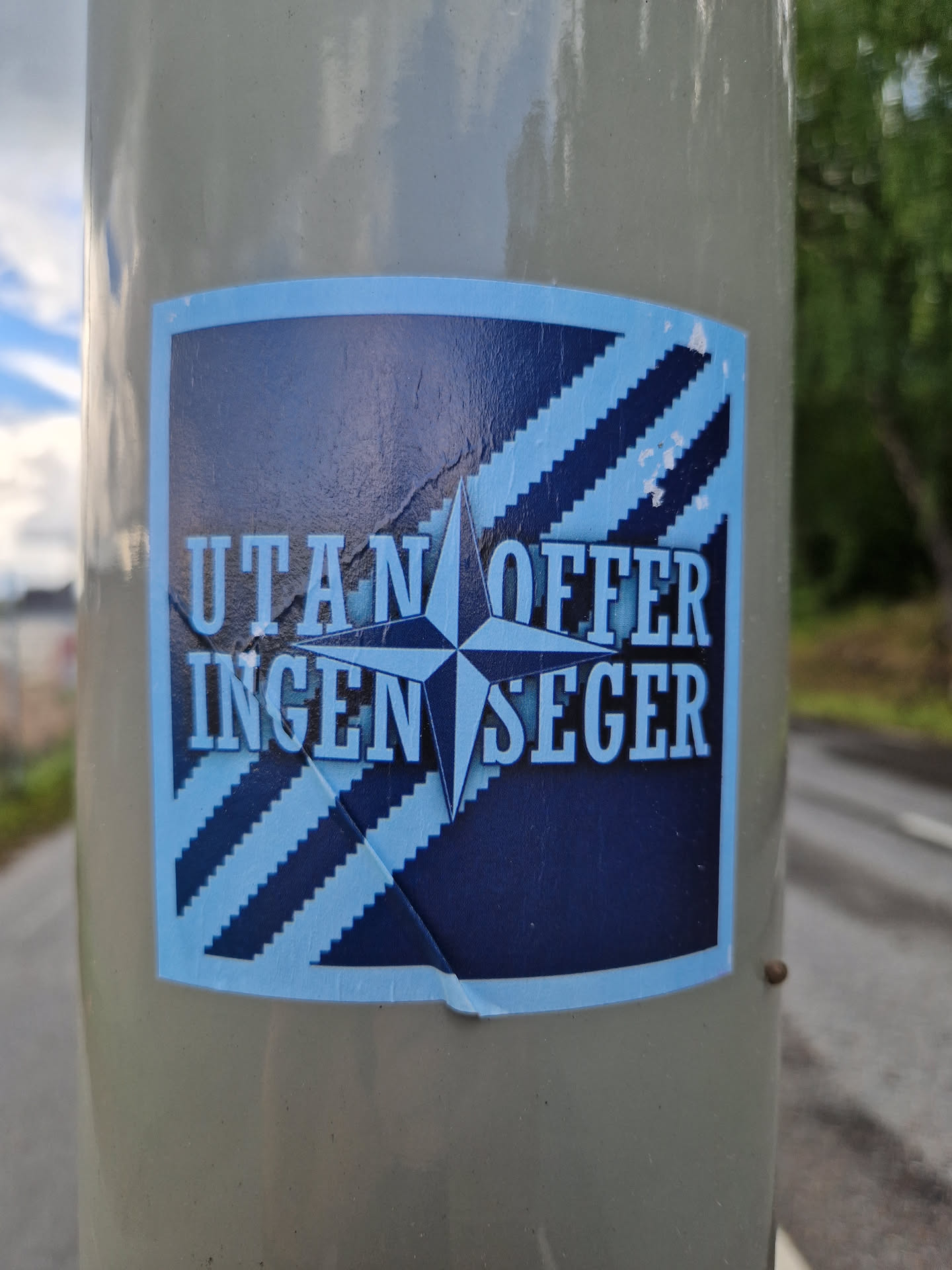 A sticker with a blue and dark blue color scheme. It has a compass rose in the center and text that says "UTAN OFFER INGEN SEGER" which translates from Swedish to English as "No Offer, No Victory".