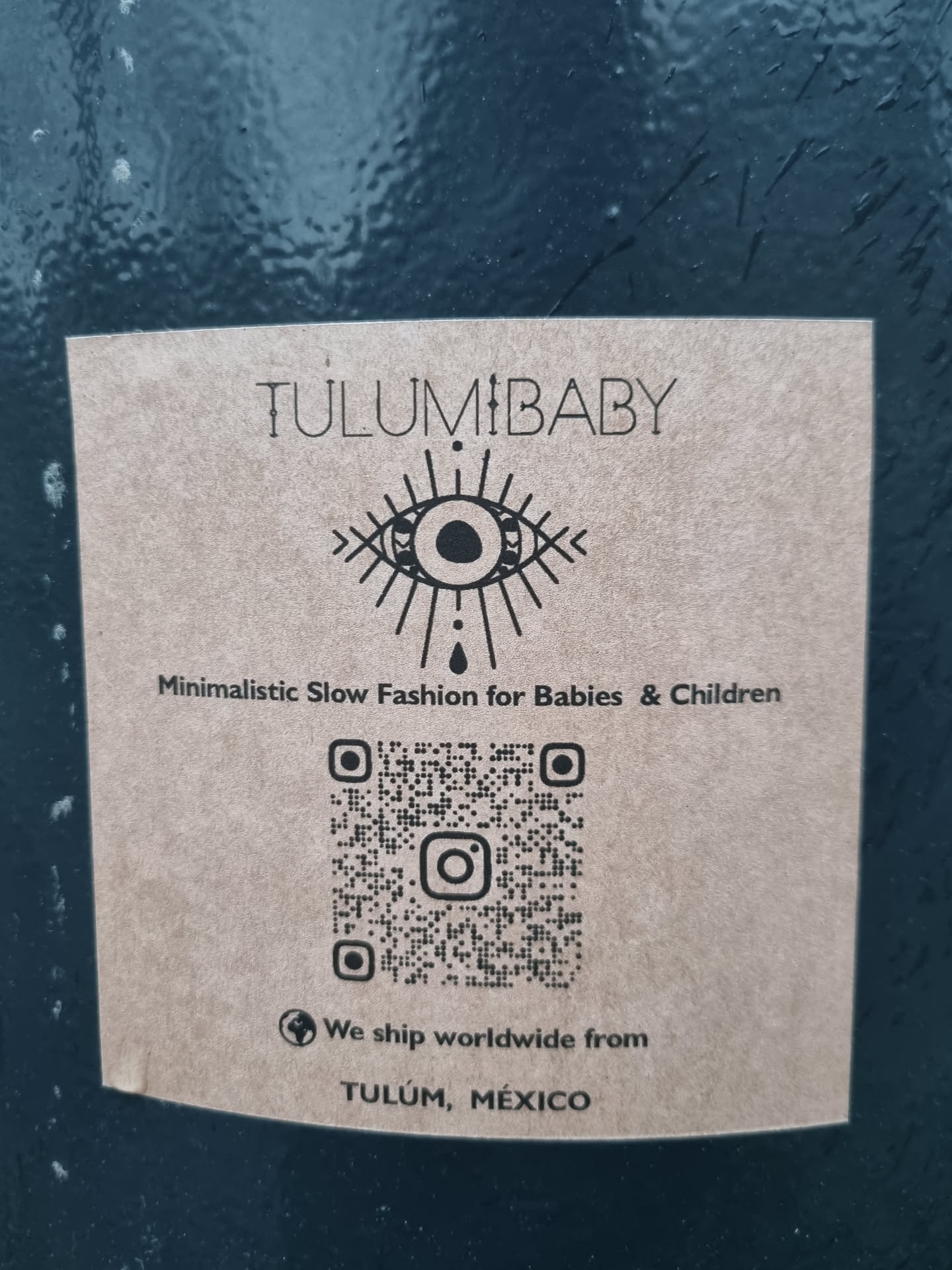 Brown sticker with the logo of Tulum Baby, including an eye symbol and a QR code linking to their Instagram.  They ship worldwide from Tulum, Mexico.