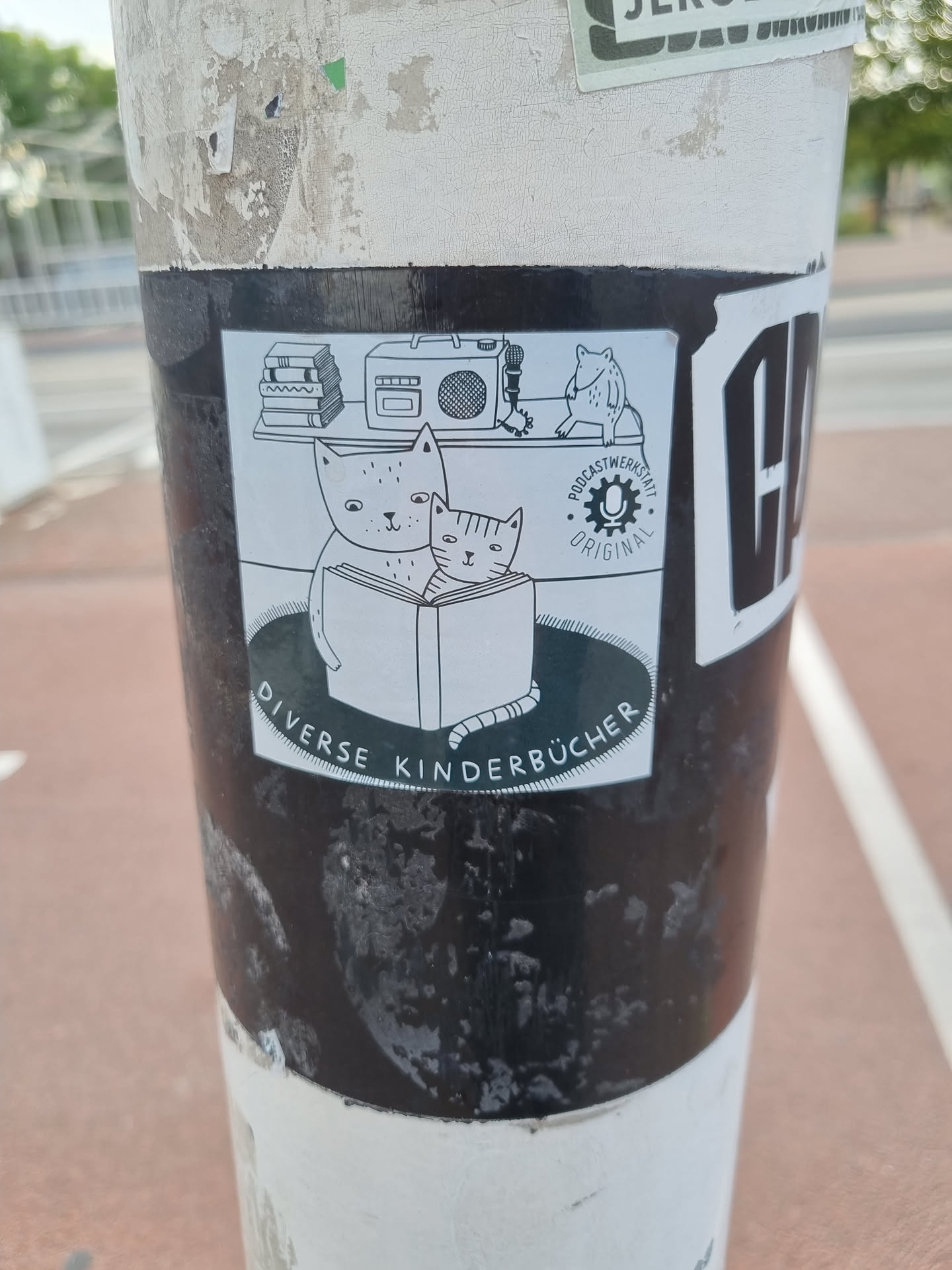 A sticker featuring an illustration of two cats reading a book, surrounded by other objects like books, a boombox, and a small figure. The text at the bottom reads 'Diverse Kinderbücher', which translates to 'Diverse Children's Books' in German.  There's also a logo that includes 'Podcastwerk' and 'Original'.