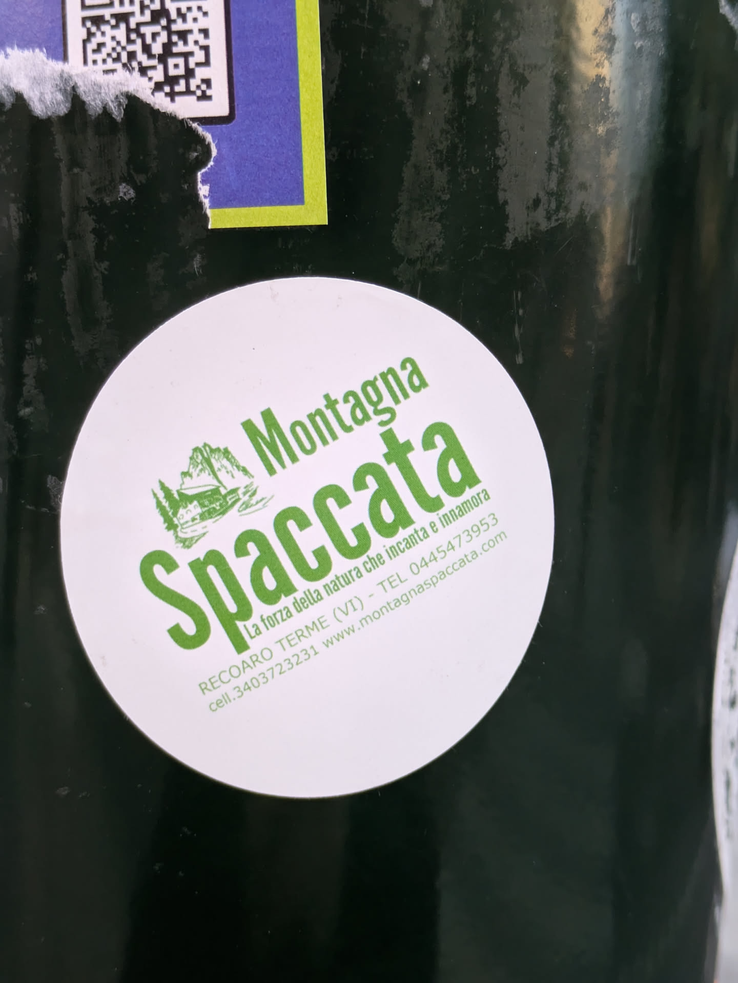 A round sticker featuring the logo of Montagna Spaccata, a natural site in Recoaro Terme, Italy. The logo includes a green illustration of mountains and text that translates to "The power of nature that enchants and inspires love." Contact information, including a website and phone number, is also listed.