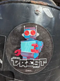 Round sticker featuring a retro-futuristic robot illustration with red eyes and a teal body. The text 'DREST' is prominently displayed below the robot in a stylized font, along with 'STYLEWRITING' and 'SINCE 1995'.  An Instagram handle is included at the bottom.