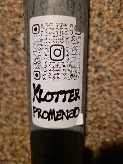 A white sticker with a QR code linking to Instagram and text saying "Klotter Promenad" in black graffiti style.