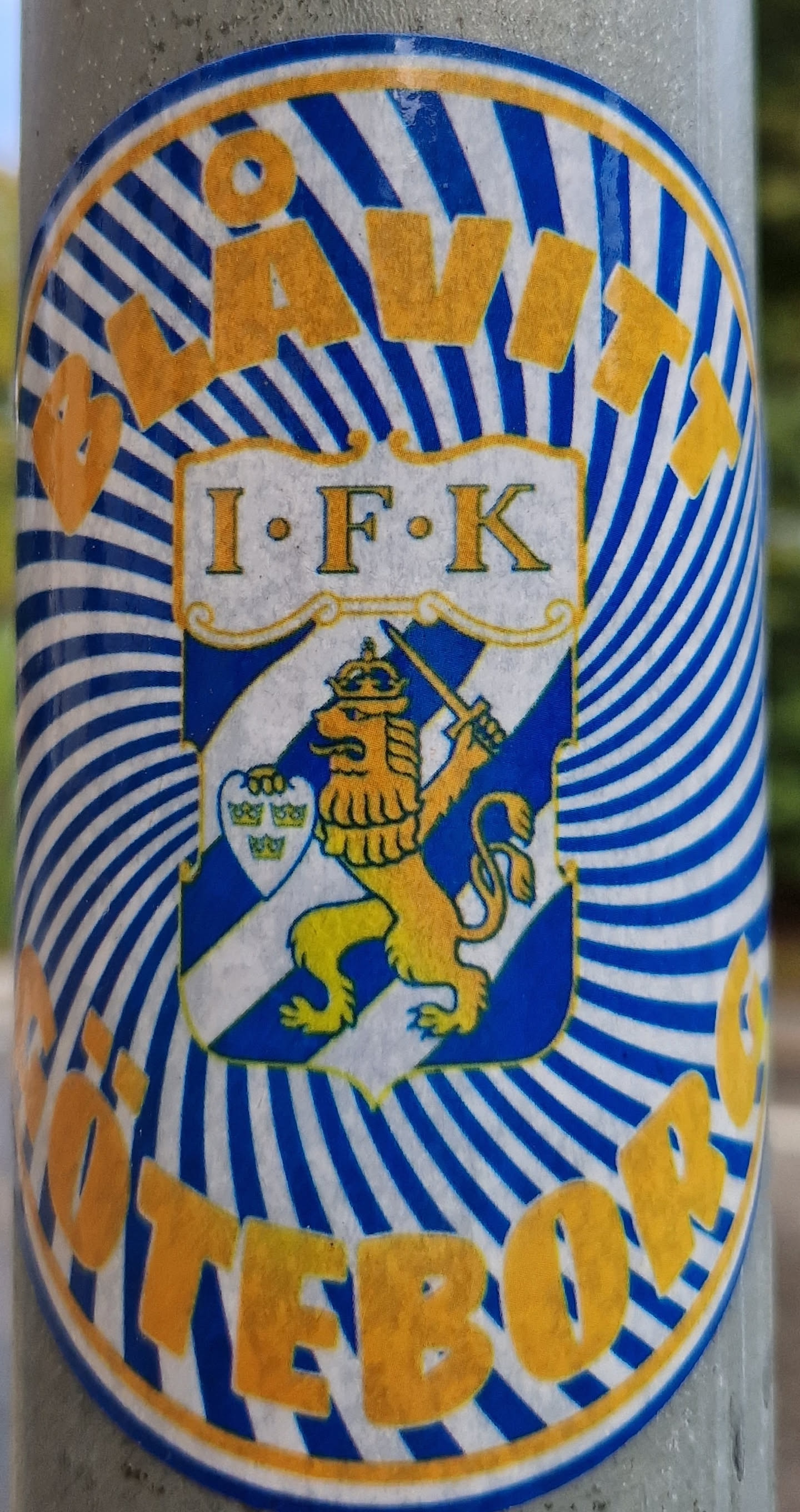 A round sticker featuring the Blåvitt (blue-white) colors and emblem of IFK Göteborg, a Swedish football club. The design incorporates a lion emblem within a shield, surrounded by a blue and white striped radial pattern. The words "Blåvitt" and "Göteborg" are written in a golden color along the top and bottom respectively. The letters I.F.K. appear above the emblem.