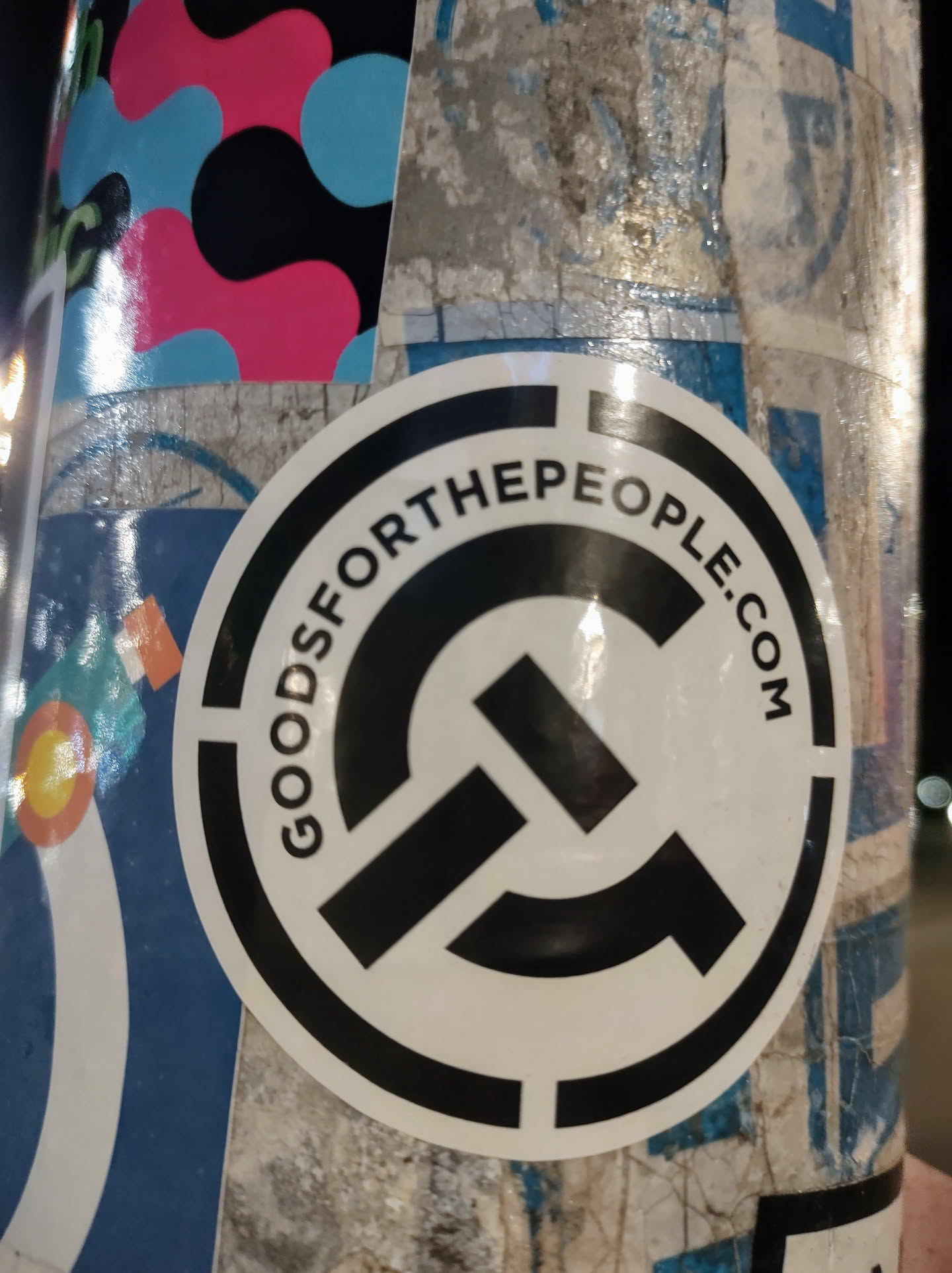 Round white sticker with a black circular design and logo. The text 'GOODSFORPEOPLE.COM' is visible around the logo. 