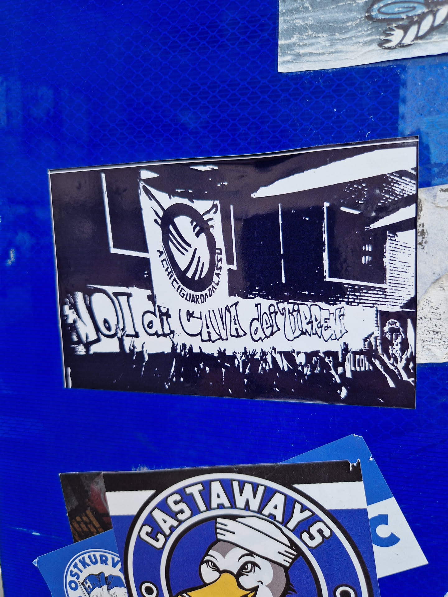 Black and white sticker depicting a building, possibly a club or bar.  Text in Spanish is visible at the bottom, and a logo-like graphic is present at the top. The overall style suggests a punk, hardcore or alternative aesthetic.