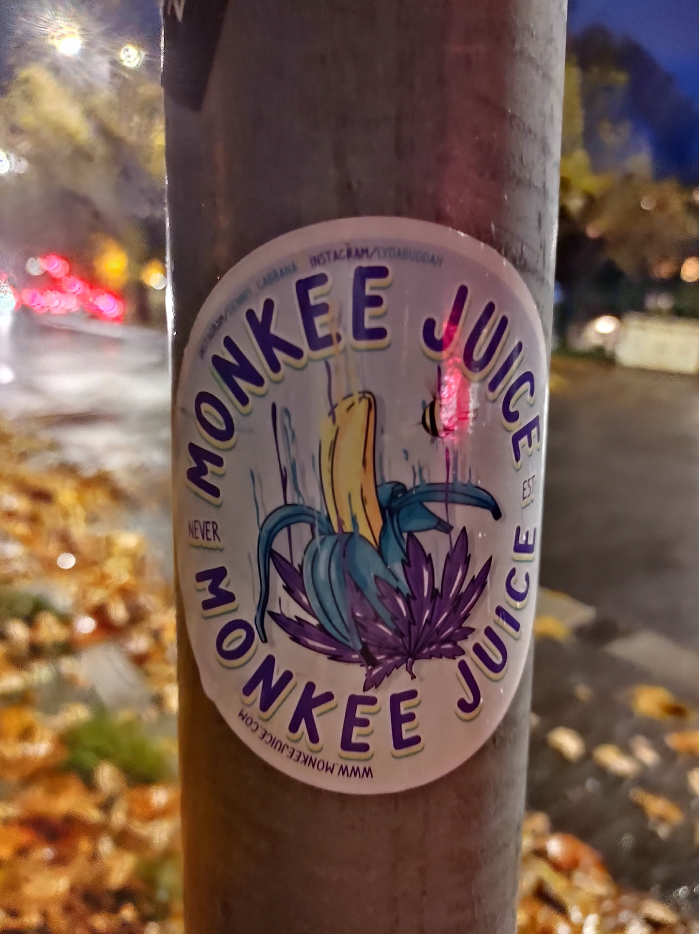 A round sticker featuring a banana with purple leaves and the text 'Monkee Juice' repeated around it.  The text 'Never' is smaller beneath the banana. A website address is also visible at the bottom.