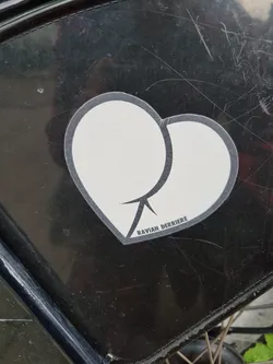 A black and white sticker depicting two overlapping circles forming a heart shape. The text "RAVIAN DERRIERE" is visible at the bottom of the sticker.