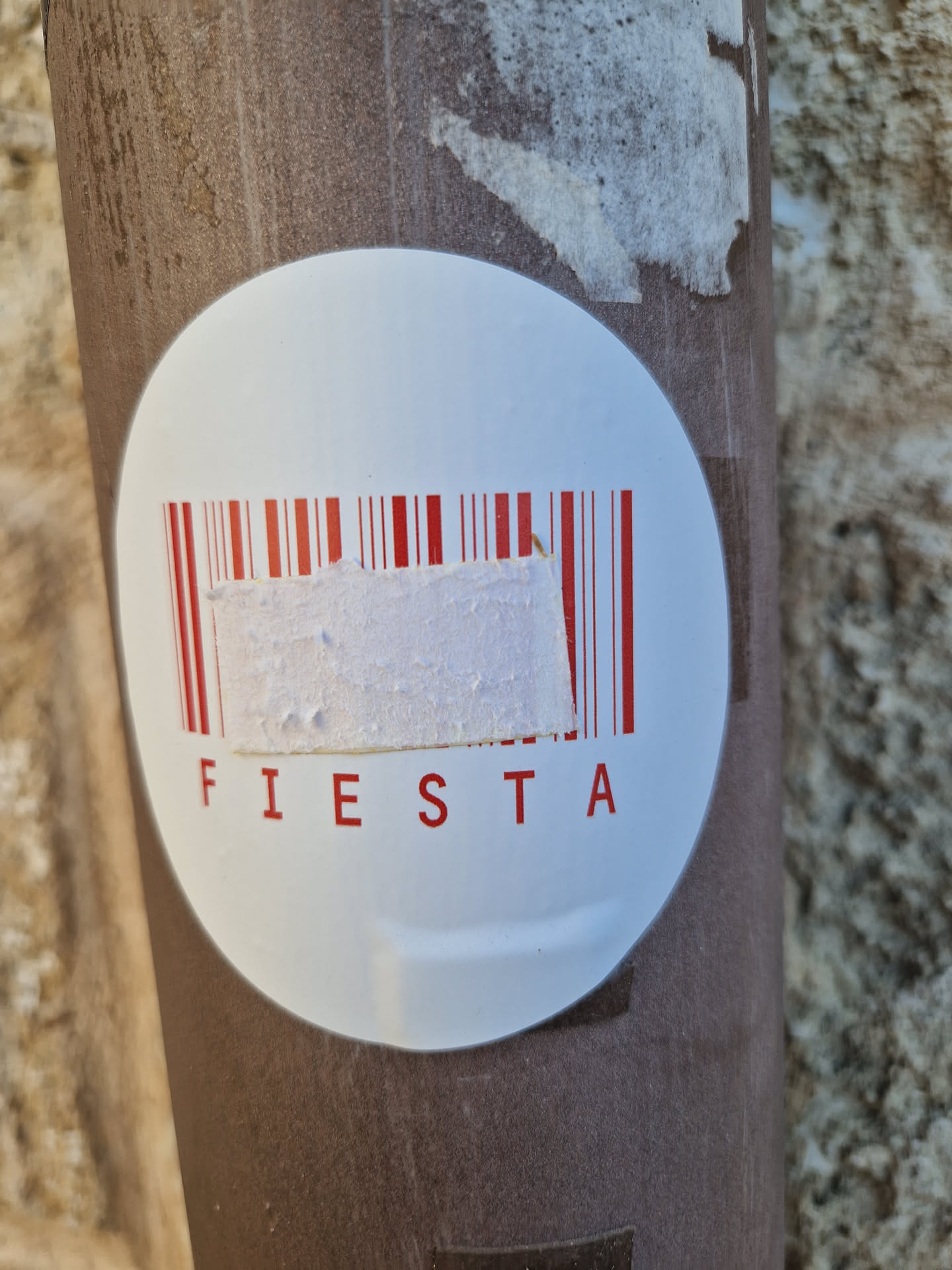 A round white sticker with a barcode and the word FIESTA in red letters.  Part of the barcode is obscured by a piece of white tape.