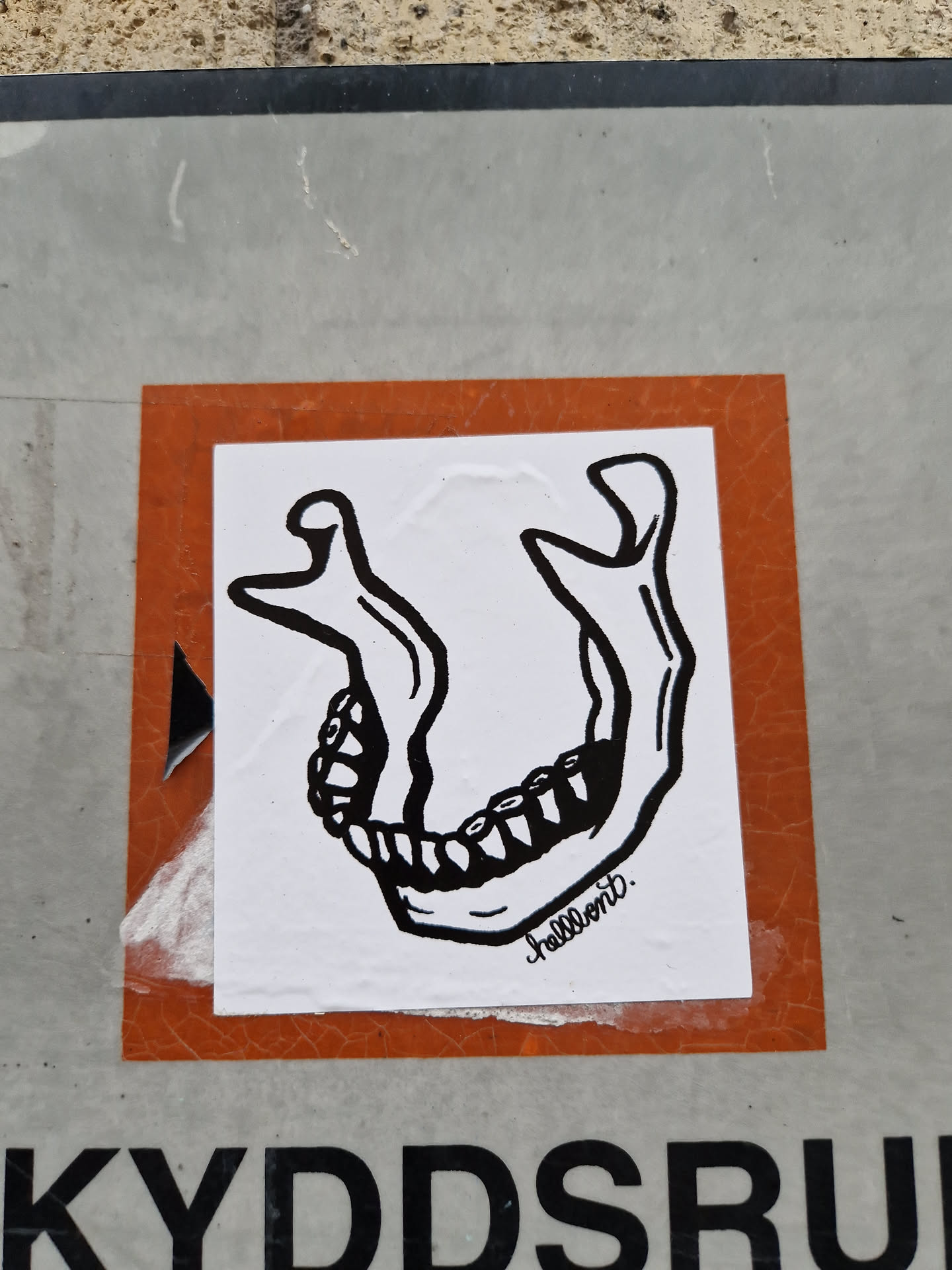 This sticker features a black and white illustration of a lower jaw with visible teeth. The style is simple and bold. The artist's signature, 'hellbent', is visible in the bottom right corner.