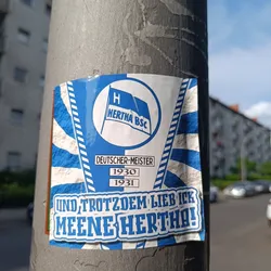 A sticker showing the logo of Hertha BSC, a German football club, with the text "Deutscher Meister" (German Champion) and the years 1930 and 1931.  The bottom of the sticker says "Und trotzdem lieb ick meene Hertha!" which translates to "And still I love my Hertha!"